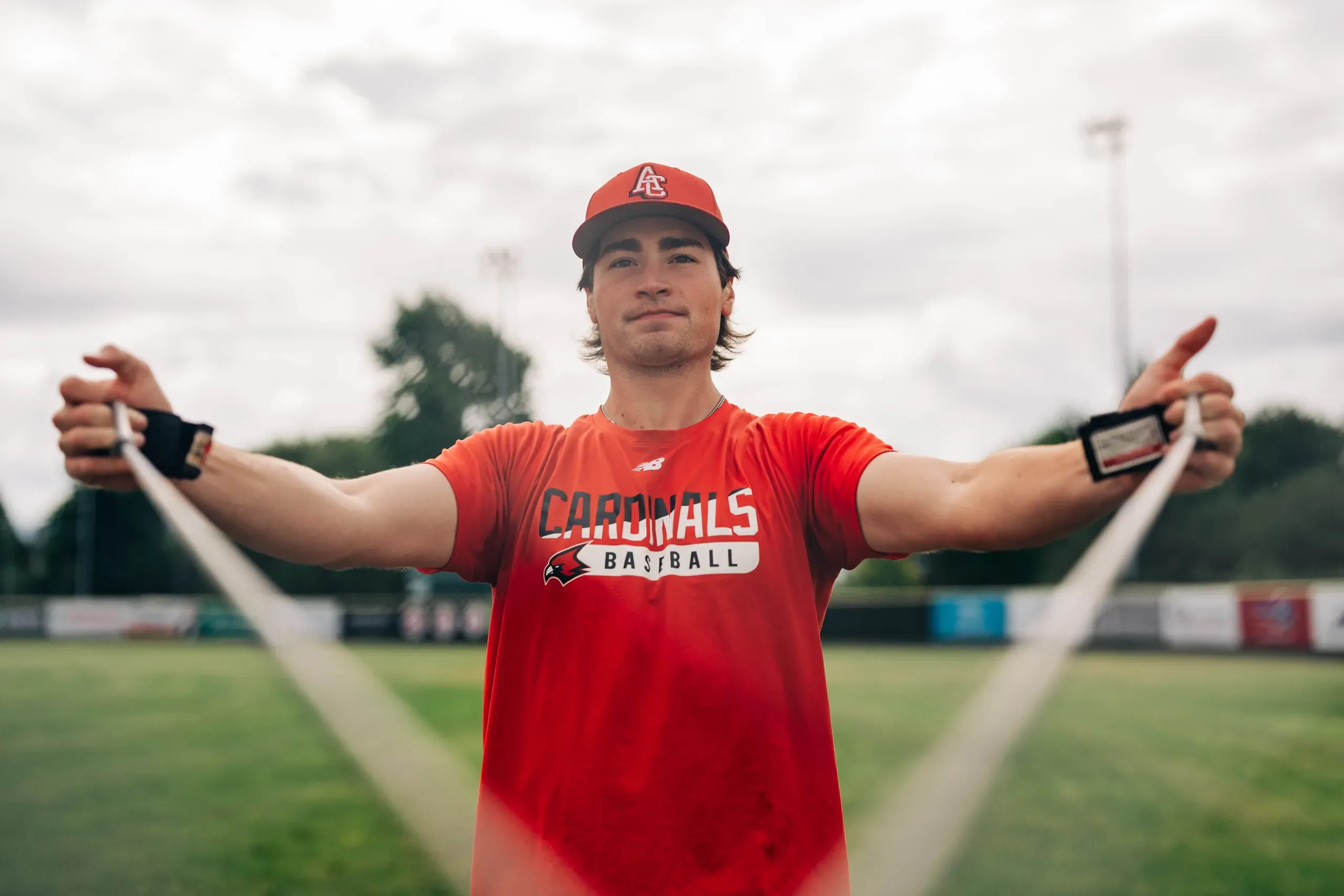 A Cardinals Premier player in a red team T-shirt, pulling a resistance band apart at the BC PBL Championships.