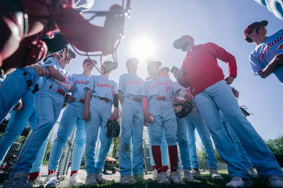 Abbotsford Cardinals players huddle together in the sun before a game.
