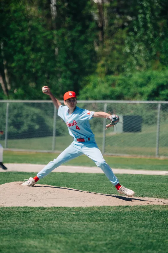 An Abbotsford Cardinals pitcher drives toward the plate during a day game.